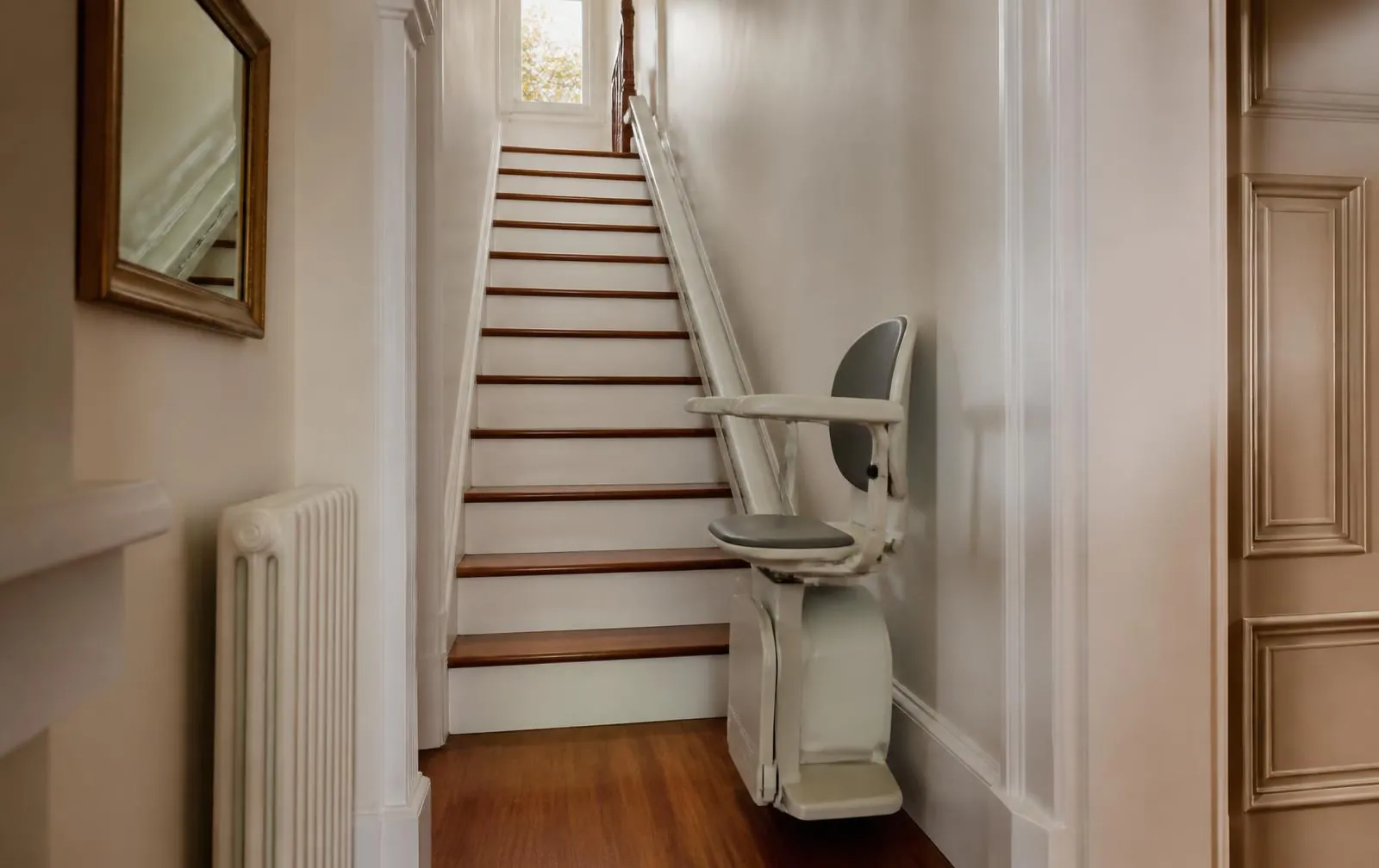 Cream stairlift installed on a narrow wood staircase in a Newton Highlands home