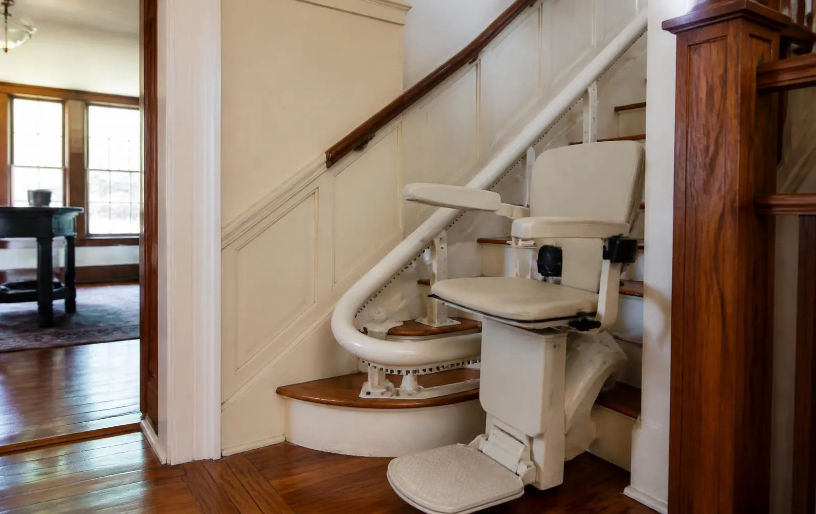 Cream stairlift following a turning hardwood staircase in a Newton Upper Falls home