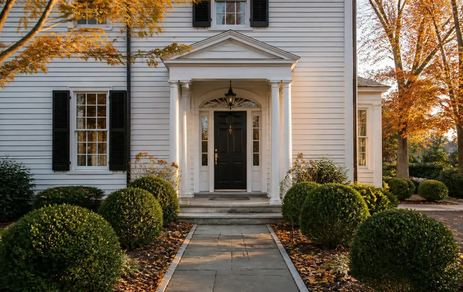 Front entry of a white colonial home in Newton, MA on an autumn afternoon