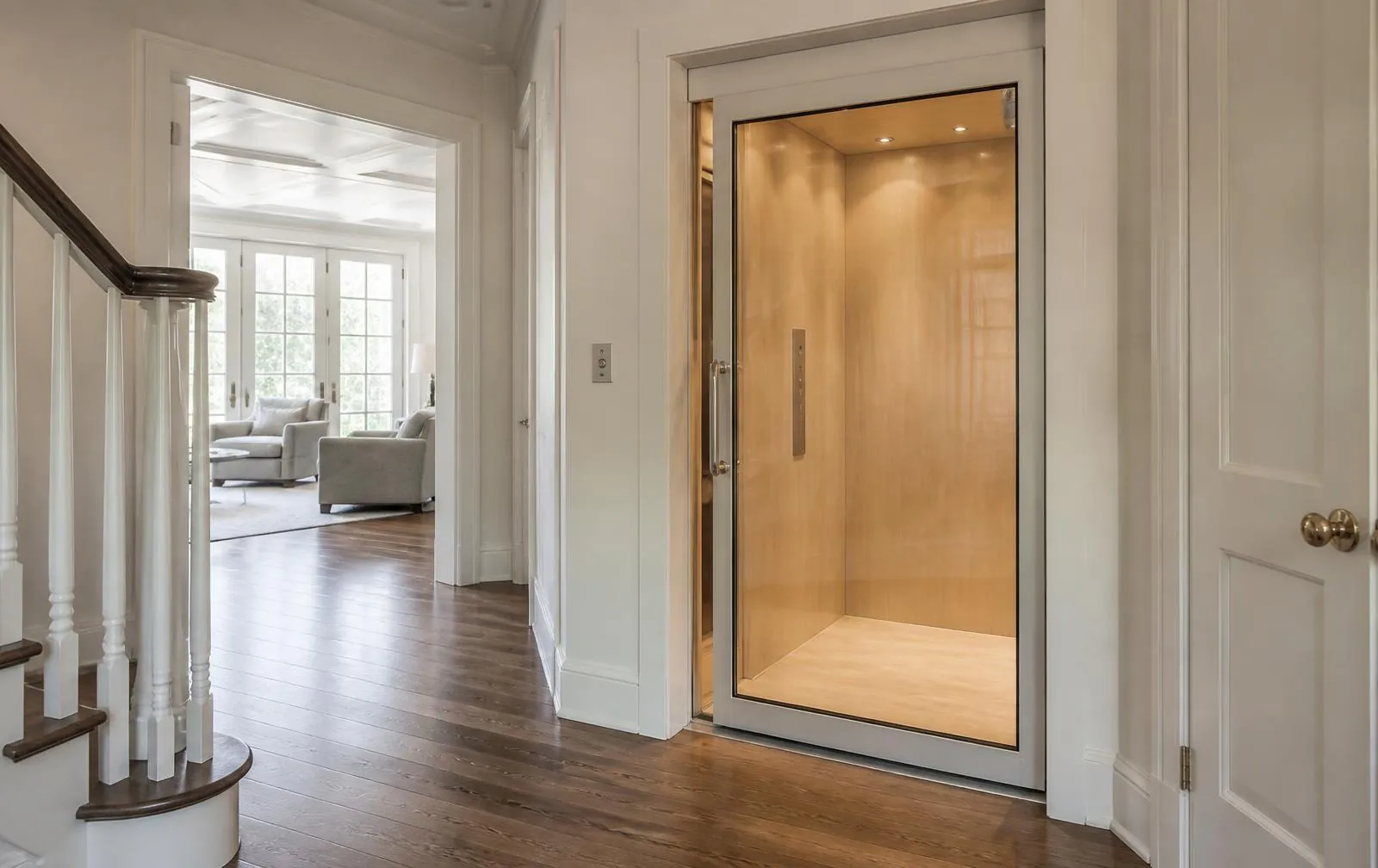 Residential home elevator with a wood cab installed in the hallway of a bright New England home
