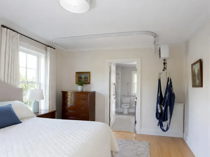 Ceiling track patient lift routed from a bedroom toward an adjoining bathroom