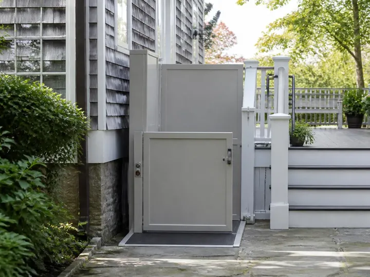 Vertical platform lift aligned with a painted porch and a stone walkway