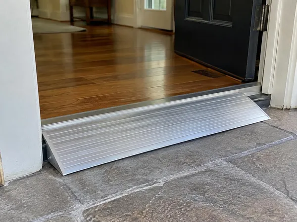 Aluminum threshold ramp bridging the raised sill of an exterior doorway
