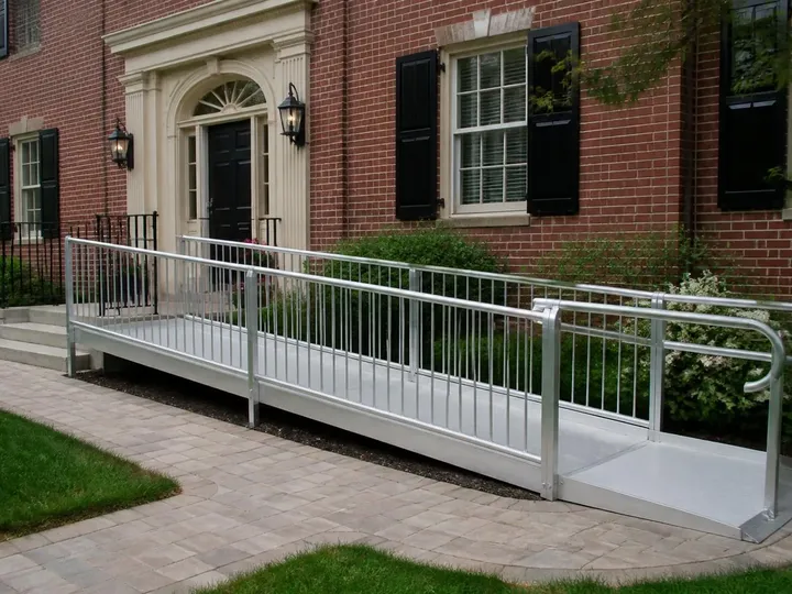 Finished modular aluminum wheelchair ramp at the entrance of a brick house